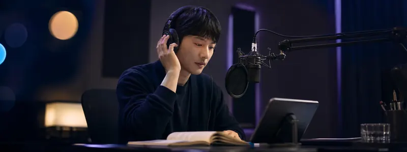 配音演员戴耳机在麦克风前用 IndexTTS2.5 演播有声书,屏幕显示配音文本